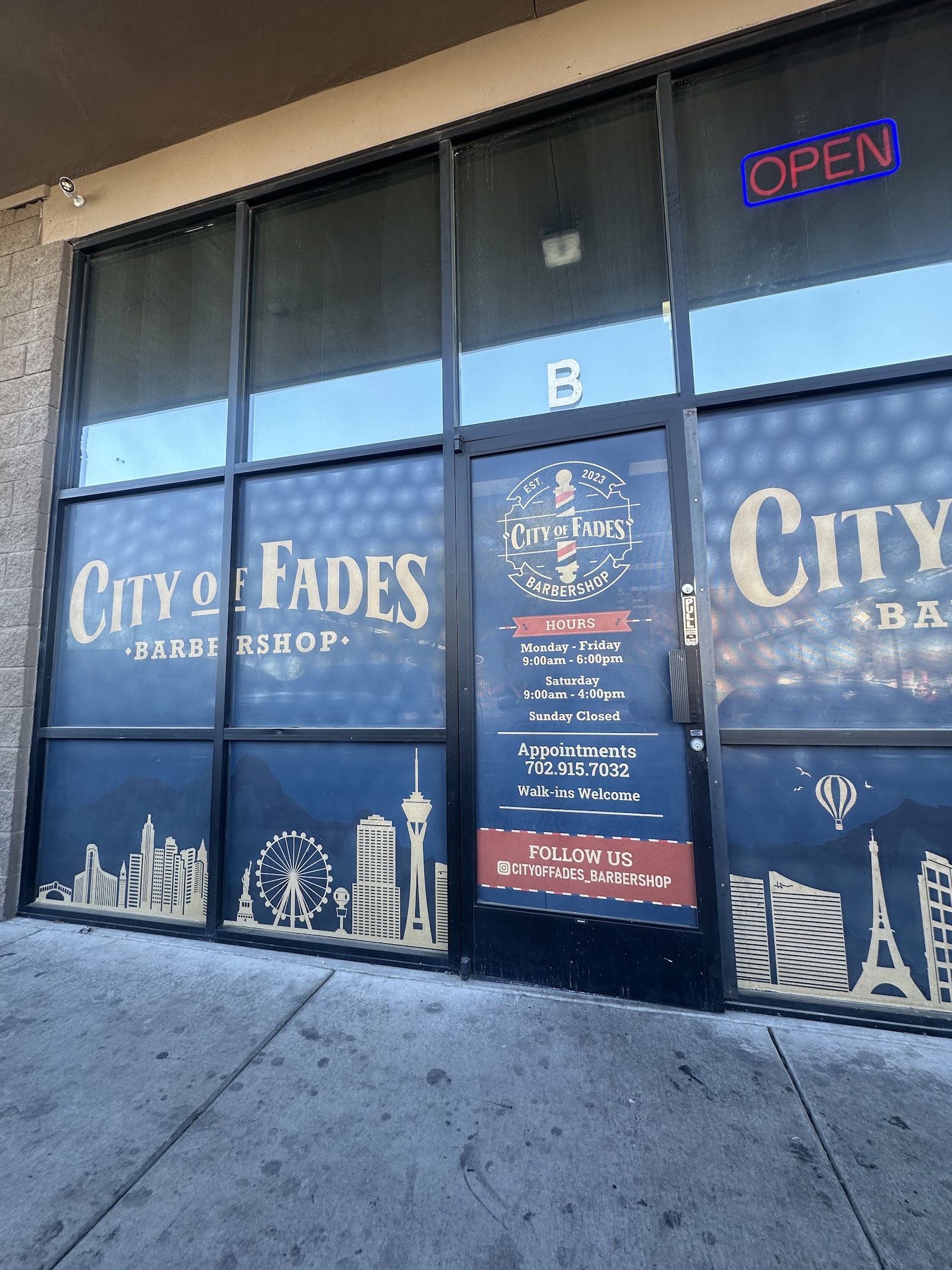 Close-up of City of Fades storefront windows with hours, phone and OPEN sign