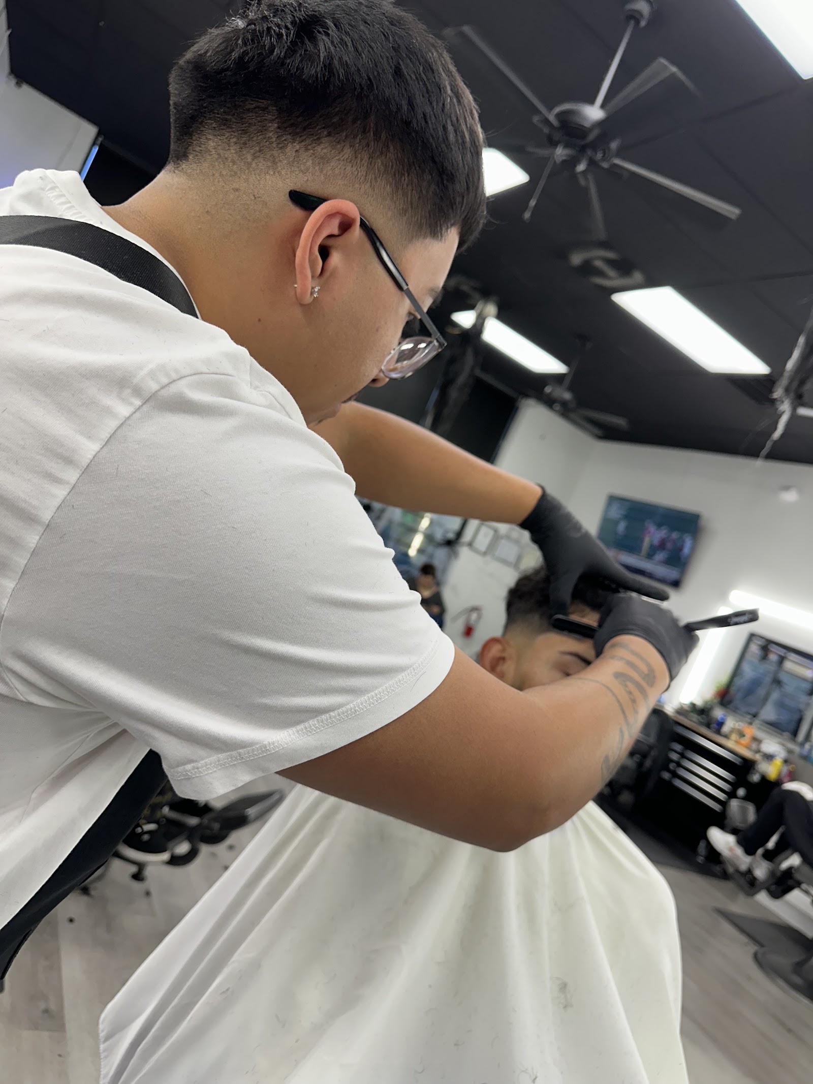 Barber with glasses giving a client a fade haircut